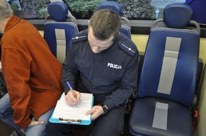 Na zdjęciu mężczyzna w policyjnym mundurze wypisuje formularz rejestracyjny dawcy szpiku.