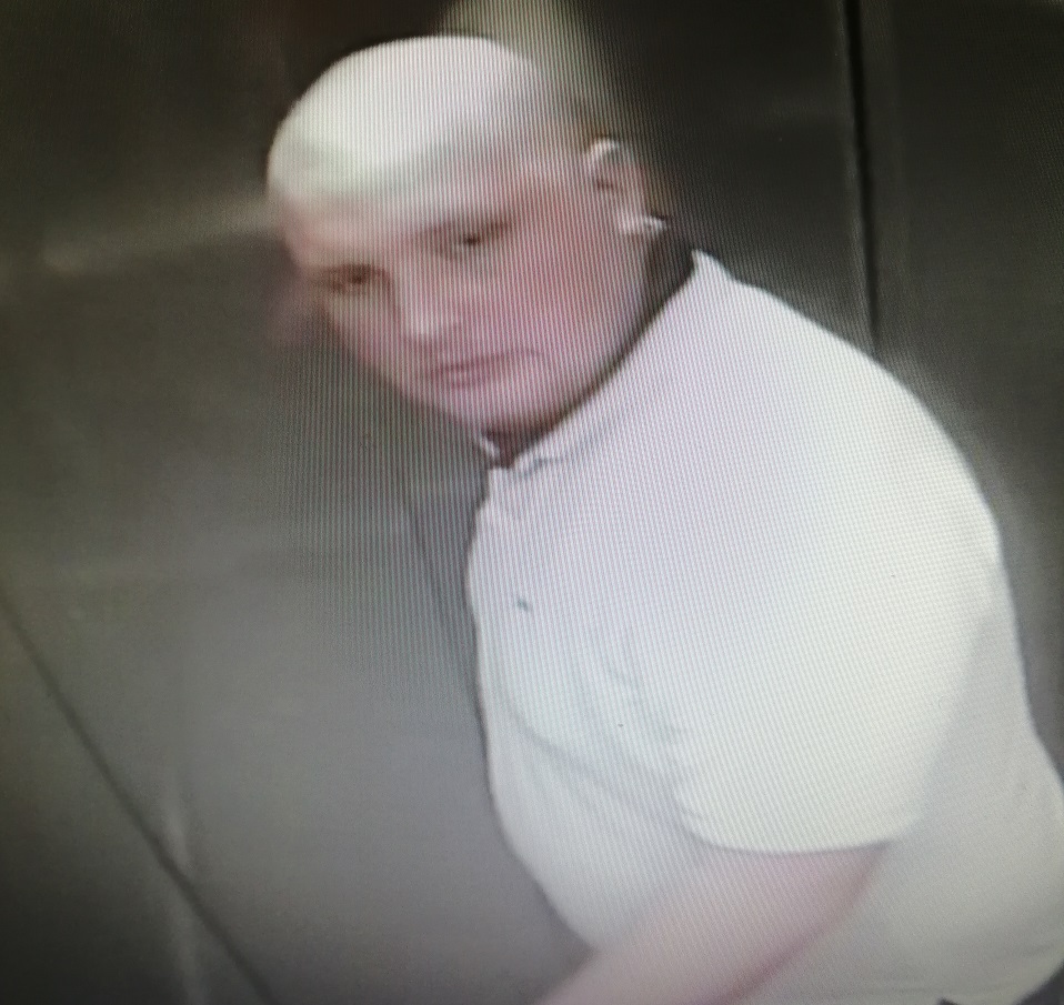 zdjęcie kolorowe: łysy mężczyzna w białej koszulce podejrzewany o zniszczenie drzwi wejściowych do budynku