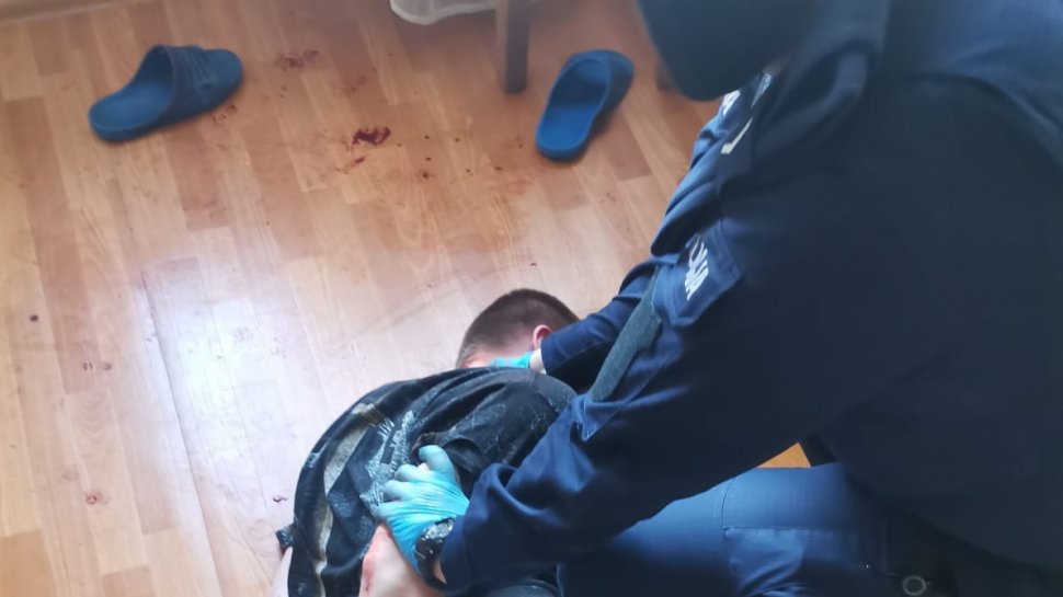 zdjęcie kolorowe:   policjanta udzielający pomocy mężczyźnie, który się samookaleczył