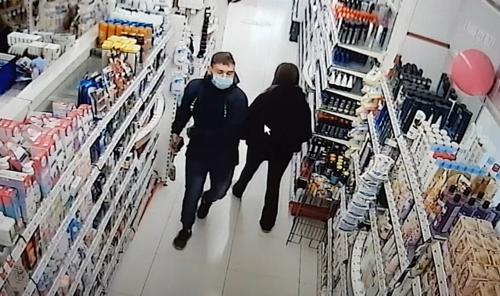 zdjęcie kolorowe: mężczyzna w czarnych spodniach i w czarnej kurtce z niebieska maseczka ochronna na twarzy w alejce sklepu kosmetycznego