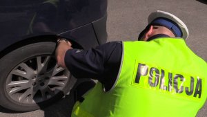 Policjant w trakcie kontroli stanu technicznego samochodu