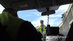 Policjant w radiowozie oraz policjant w trakcie pomiaru prędkości samochodów