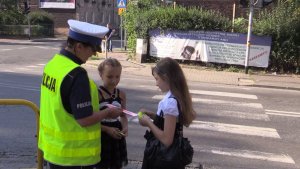 Policjantka rozdaje dzieciom odblaski