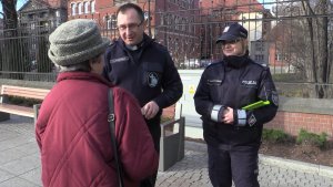 Policjanci wraz z księdzem wręczają pieszym elementy odblaskowe