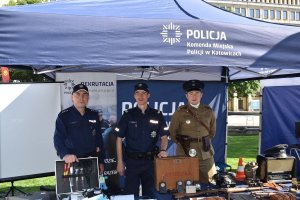 Na zdjęciu widać trzech policjantów pod namiotem z logo KMP Katowice