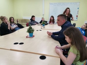 Na zdjęciach widać  dzielnicowego na spotkaniu z dziećmi, wszyscy siedzą przy stole i policjant opowiada o bezpieczeństwie.