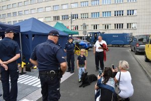 na zdjęciu widać stoisko KMP Katowice obok stoją policjanci oraz pies służbowy i dzieci