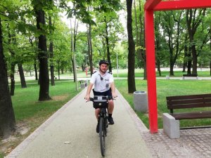 Na zdjęciu widać policjanta na rowerze jadącego przez park