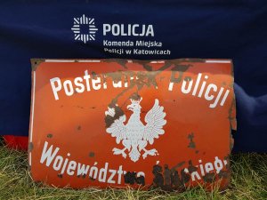 Na zdjęciu widać szyld komisariatu Policji Województwa Śląskiego z tyłu logo KMP Katowice