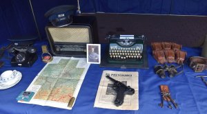Na zdjęciu widać stolik z wystawionymi eksponatami Policji Województwa Śląskiego na środku leży pistolet