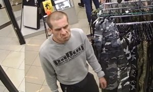 zdjęcie kolorowe: mężczyzna podejrzewany o kradzież broni i amunicji ubrany w szara bluzę dresową z czarnym napisem.