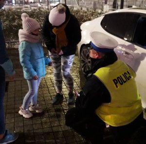 zdjęcie kolorowe: Policjant wydziału ruchu drogowego katowickiej komendy rozmawiający na chodniku z kobieta i dzieckiem
