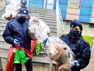 Zdjęcie kolorowe,umundurowani policjanci niosący prezenty świąteczne.