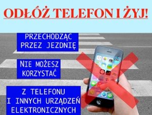 zdjęcie kolorowe: plakat promujący akcję &quot;Odłóż telefon i żyj&quot; przedstawiający na tle przejścia dla pieszych telefon komórkowy trzymany w dłoni. Poniżej obowiązujące przepisy prawa w tym zakresie