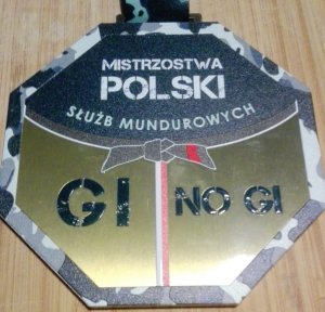 zdjęcie kolorowe: druga strona medalu na którym umieszczono napis o treści Mistrzostwa Polski Służb Mundurowych