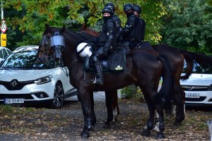 zdjęcie kolorowe: policjanci w służbie konnej podczas zabezpieczenia meczu nadzorujący przemarsz kibiców