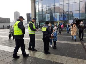 zdjęcie kolorowe: funkcjonariusz Policji, Wojewódzkiego Inspektoratu Transportu Drogowego i straży miejskiej stojący na placu przed dworcem PKP podczas działań &quot;Błyśnij dla życia&quot;