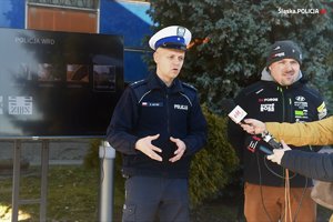 zdjęcie kolorowe: policjant wydziału ruchu drogowego KWP Katowice i kierowca rajdowy Jarosław Szeja podczas rozmowy z dziennikarzami