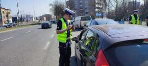 zdjęcie kolorowe: policjant katowickiej drogówki kontrolujący pojazd osobowy w trakcie działań NURD