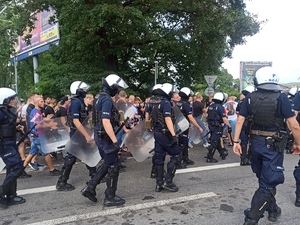 zdjęcie kolorowe: policjanci oddziału prewencji podczas przemarszu na stadion z pseudokibicami