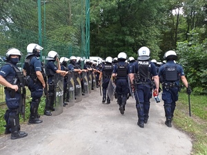 zdjęcie kolorowe: policjanci oddziału prewencji oczekujący na przybycie pseudokibiców