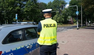 zdjęcie kolorowe: policjant ruchu drogowego stojący przy radiowozie