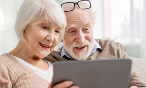 zdjęcie kolorowe: starszy pan i starsza kobieta trzymający tablet w dłoni