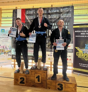 zdjęcie kolorowe:  starszy posterunkowy Łukasz Banach na podium wraz z zawodnikami, którzy zajęli II i III miejsce