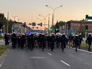 zdjęcie kolorowe: policjanci oddziału prewencji w asyście kroczącej prowadzą kibiców na stadion