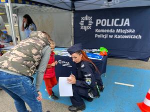 zdjęcie kolorowe: policjantka i policyjne stanowisko profilaktyczne podczas Pikniku z Bebokiem