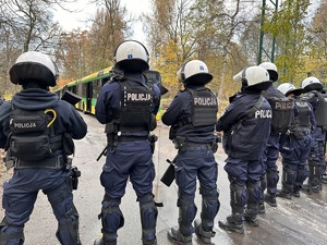 zdjęcie kolorowe: policjanci oddziału prewencji nadzorujący przemarsz pseudokibiców na stadion