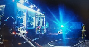 zdjęcie kolorowe: policyjny radiowóz i straży przed kamienicą w której wybuchł pożar