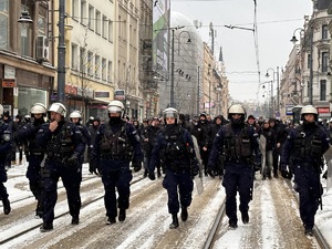 zdjęcie kolorowe: policjanci maszerujący z pseudokibicami w kierunku katowickiego Rynku