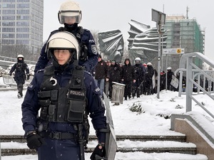 zdjęcie kolorowe: policjanci maszerujący z pseudokibicami w rejonie pomnika Powstańców Śląskich