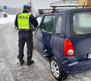 zdjęcie kolorowe: policjant katowickiej drogówki podczas kontroli pojazdu osobowego