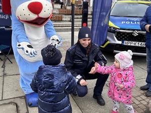 zdjęcie kolorowe: Sznupek i policjantka podczas rozmowy  z dziećmi