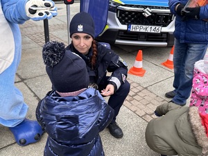 zdjęcie kolorowe: Sznupek i policjantka podczas pamiątkowego zdjęcia z dziećmi