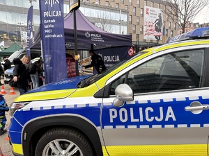 zdjęcie kolorowe: policyjny radiowóz i stoisko profilaktyczne katowickiej komendy